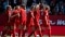 Das Bild zeigt eine Gruppe von Fußballspielern des FC Bayern München, die sich auf dem Spielfeld umarmen
