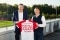 Das Bild zeigt Andreas Jung, CMO FC Bayern und Thomas Heim, CEO Viessmann Climate Solutions vor einem Fußballfeld mit einem Trikot in der Hand