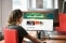 The image shows a woman infront of a desktop.
