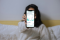Das Bild zeigt eine Frau, die ein Smartphone in die Kamera hält, auf der die App Ostrom geöffnet ist.