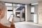 Auf dem Bild sieht man einen Mann der das Viessmann Energiesystem, einschließlich des Stromspeichers Vitocharge VX3, über eine Smartphone-App steuert. Durch ein Fenster sind eine Photovoltaikanlage und ein ladendes Elektroauto zu sehen.