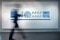 The image shows a blurred, passing person in front of a graphic.