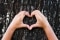 The image shows hands forming a heart in front of a tree.